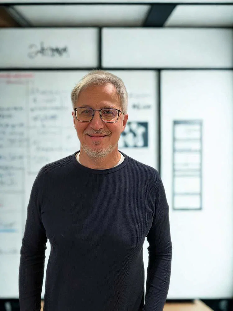 Ivo Ryssel steht lächelnd in einem Büro.